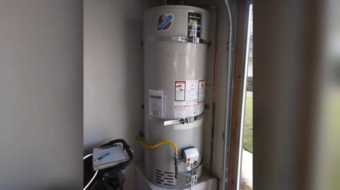 Gas water heater standing beside a wall with a yellow gas line and a small gray controller at the base
