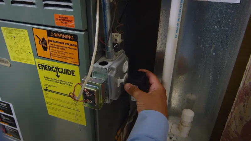 Gas control and a yellow Energy Guide label on the front of a water heater with a hand at the edge
