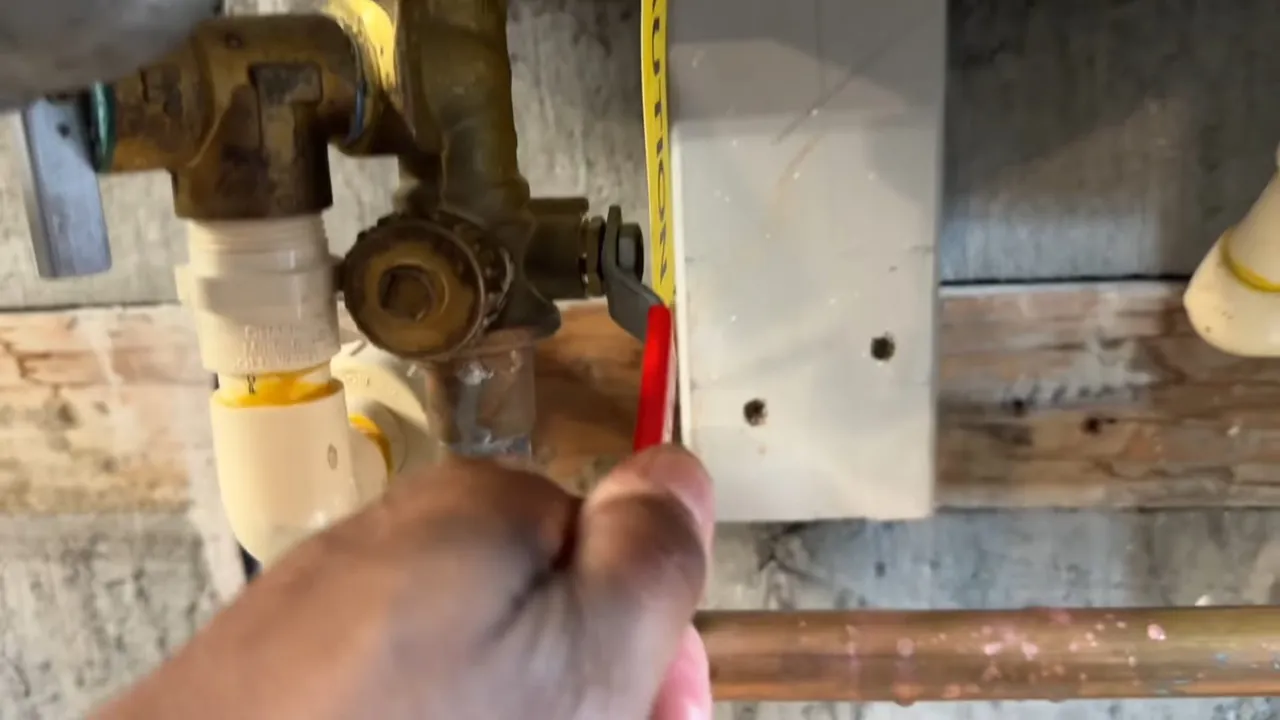 Hand holding a tape measure at brass gas fittings and white pipe next to a copper line