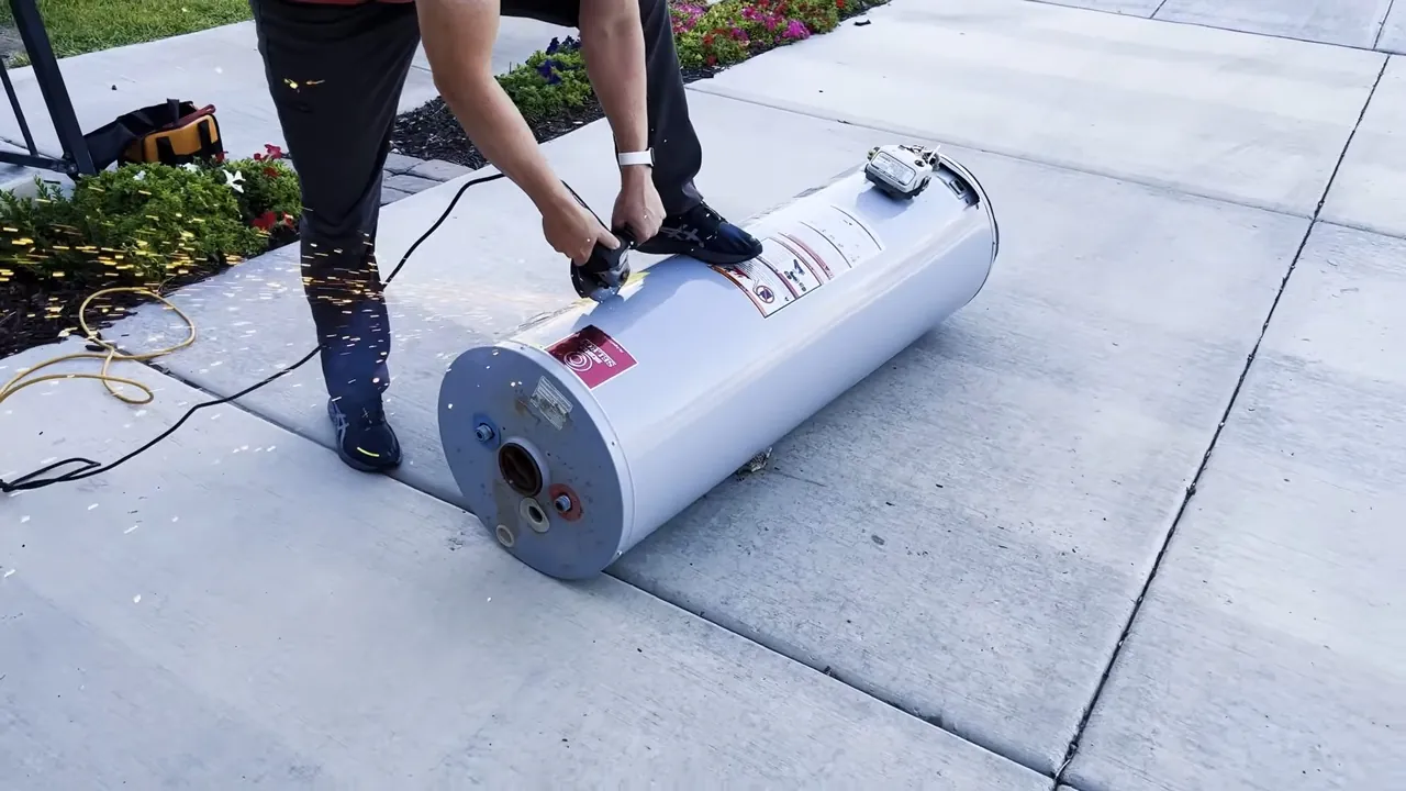 Person in black pants rolling a new white water heater tank on its side along a sidewalk