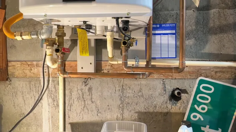 Tankless water heater with copper pipe, a yellow gas connector and a condensate line mounted on a stucco wall