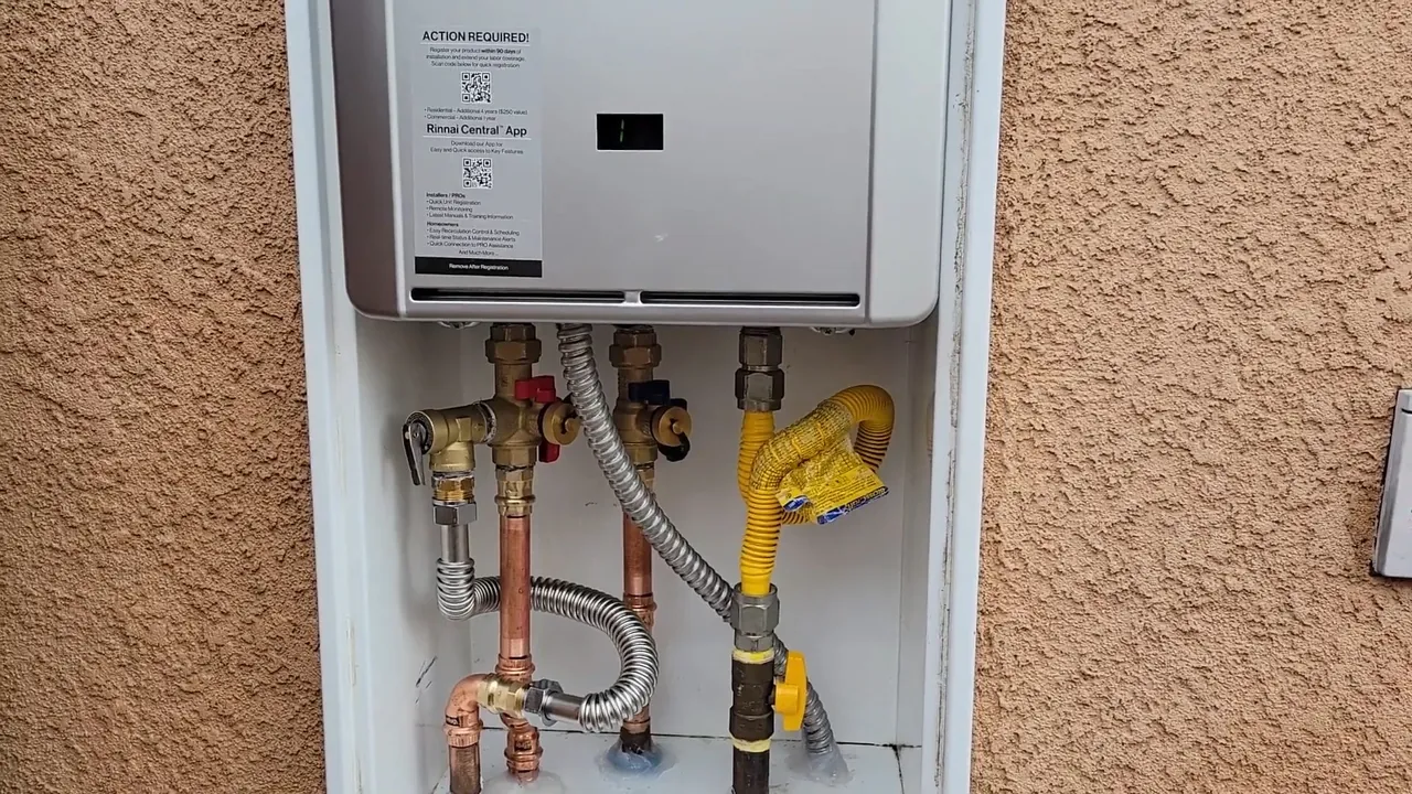 Tankless water heater mounted in a recessed wall cabinet on a stucco wall with copper, gas and flex lines below
