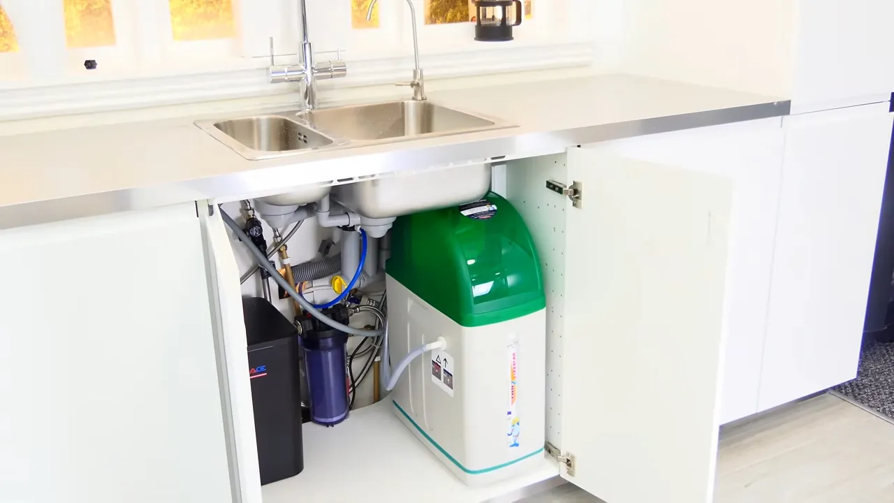 Open white sink cabinet showing an under-sink reverse osmosis system with a green tank and filter cartridges