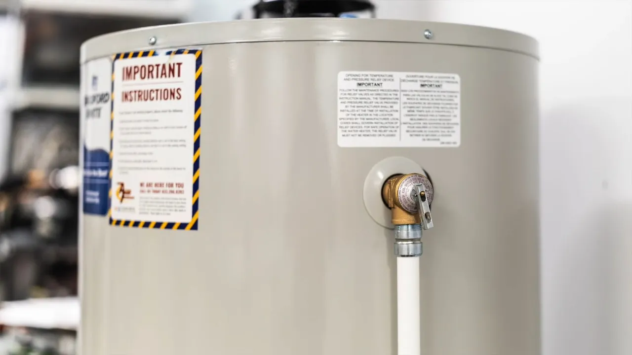 Water heater tank with an instruction label and a brass drain valve with white tubing